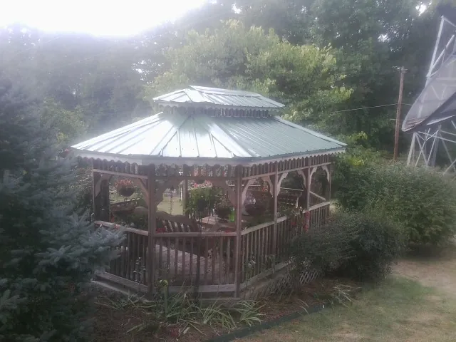 Green metal roof on a backyard gazebo surrounded by garden beds in Brooksville