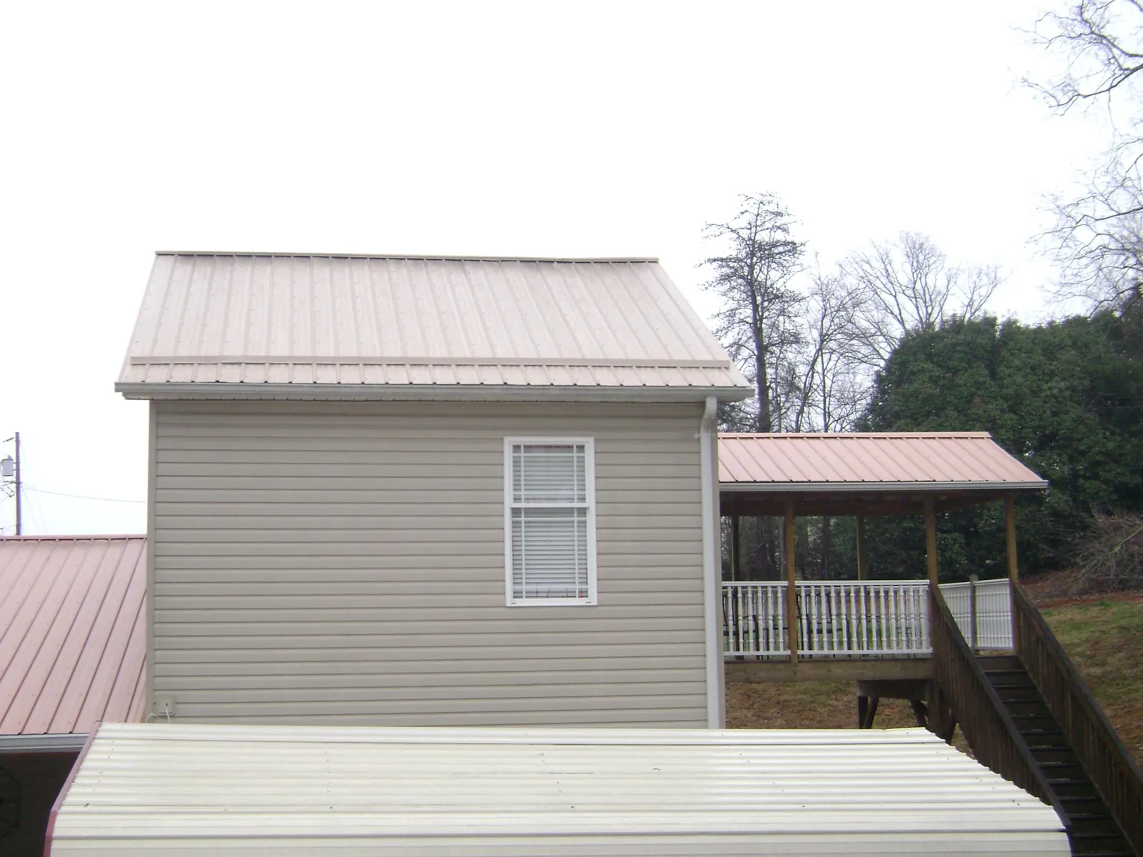 Tan metal roofs on a two story addition and attached porch, from a Roof Replacement job in Brooksville
